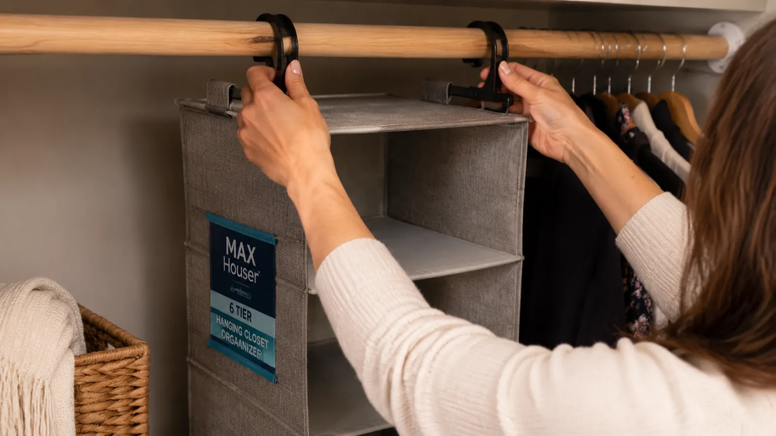 Woman clipping a hanging fabric shelf organizer onto a closet rod